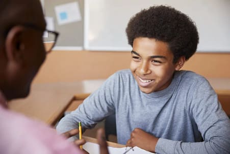 A smiling teenage boy during a session with his tutor.