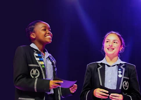 Two students in school uniform having a presentation on stage in school.